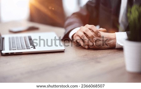 a man sits at a table with his hands clasped together close-up