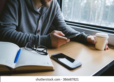 The Man Sits At A Table In A Train With A Tablet In Hands