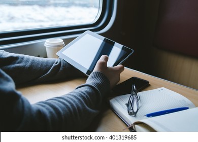 The man sits at a table in a train with a tablet in hands - Powered by Shutterstock