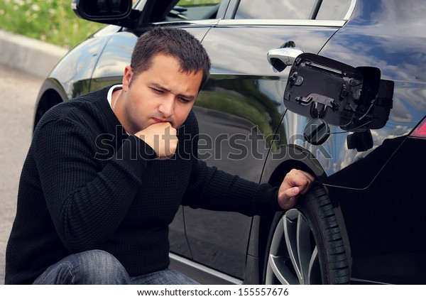 man sits and thinks next\
to the car