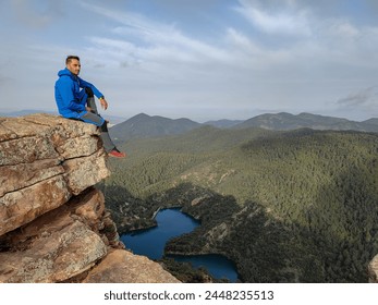 Man sitting alone looking into the void in the famous rock formations known as the Benitandus Organs. Alcudia de Veo. Spain - Powered by Shutterstock