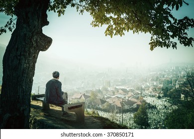 Man Sitting Alone On Bench And Watching The City