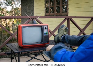 A Man Sitting Alone Watching Old TV Outside The House.