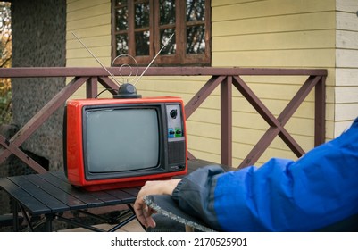 A Man Sitting Alone Watching Old TV Outside The House.