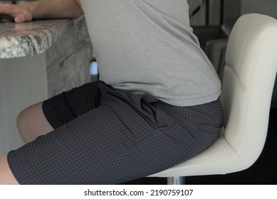 Man sitting with anterior pelvic tilt. His pelvis is tilted forward as he sits in a chair.
