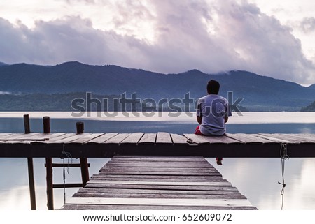 The man is sitting back and lonely emotion with the scenery in the early morning.