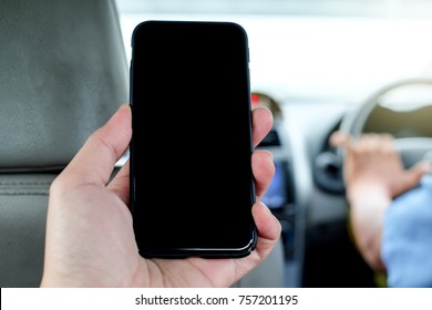 Man Sitting In Back Seat Of Taxi And Left Hand Grabbing Cellphone For Use Mobile Application.