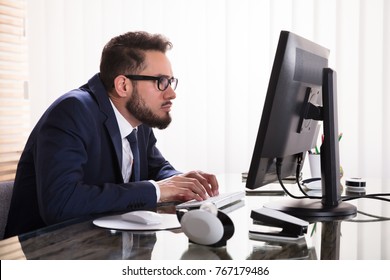 Man Sitting In Bad Posture Working On Computer In Office