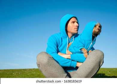 Man Sitting With Best Friend Dog In Matching Blue Hoody Sweatshirts On Bright Green Grass Meadow