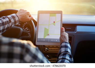 Man Sitting In Car And Holding Tablet With Map Gps Navigation, Toned At Sunset.