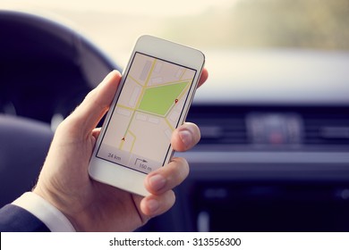 Man Sitting In The Car And Holding White Mobile Phone With Map Gps Navigation, Toned