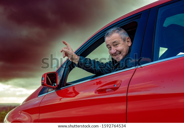 Man is\
sitting in the car and pointing at bad\
weather