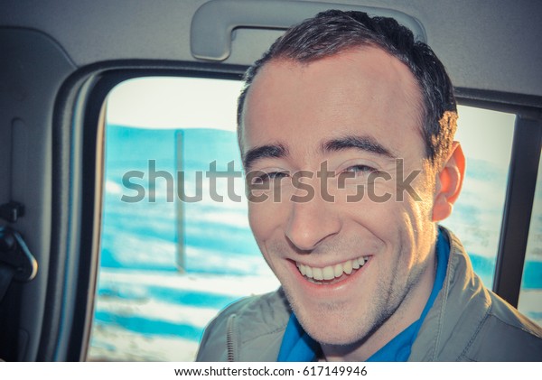 man sitting in car and\
smiling