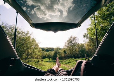 man sitting in car trunk looking at forest. beautiful landscape view. road trip concept