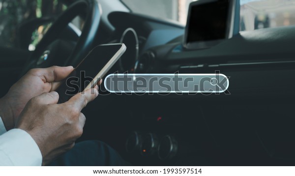 A man\
sitting in a car is using a mobile phone to search for online\
services using a mobile application, the concept is the convenience\
of finding things anywhere through a mobile\
device.