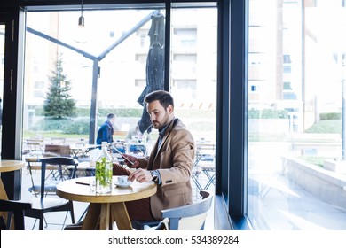Man at Sitting in Coffee Shop and Using Tablet - Shutterstock ID 534389284