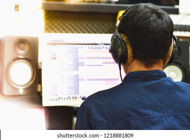 A man sitting computer screen.
He intended to make the job well.
He is remixing music.
He is a producer.