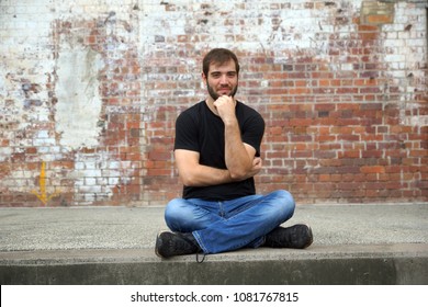 Man sitting crosslegged in front of brick wall