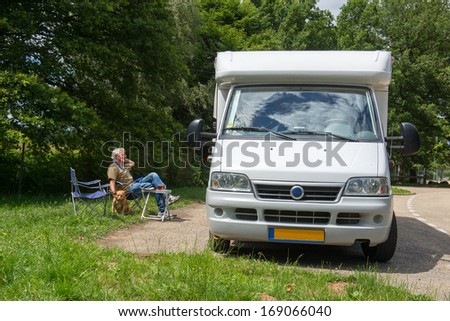 Man sitting with dog having a break with mobil home