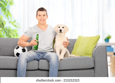 Man Sitting With Dog On Couch And Holding Beer At Home