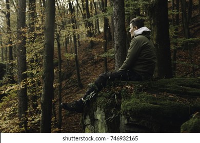 Man Sitting in Fall Forest on Moss Rock 