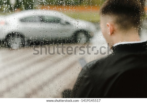 Man sitting in\
front of his car under the\
rain