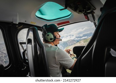Man sitting in helicopter cabin while flying over Italian Alps