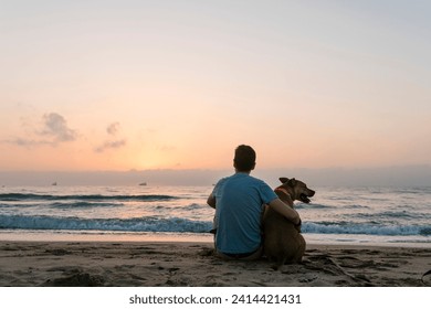 Man sitting with his dog enjoying dawn at beach - Powered by Shutterstock