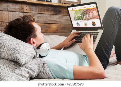 Man Sitting At Home Using A Laptop To Search For Travel Destination.