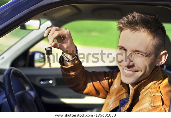 Man
sitting inside car and showing keys to new car
