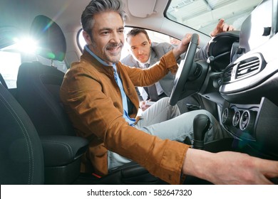 Man Sitting Inside Vehicle In Car Dealership