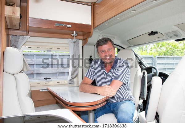 man sitting interior of camping car\
motor home in vanlife style in modern\
campervan