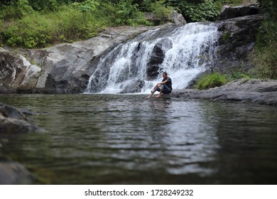 Man sitting at Khlong Nam Lai waterfall in Klong Lan national park, Kamphaeng Phet, Thailand