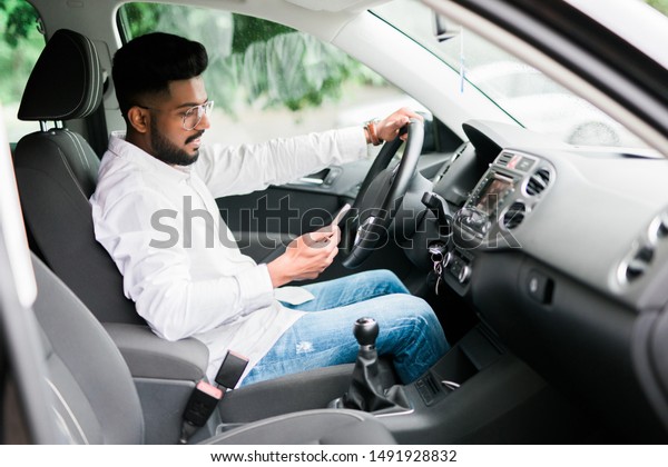 Man sitting on backseat taxi car and\
hand holding smartphone to use online\
application.