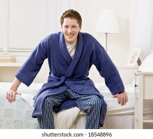 Man Sitting On Bed In Bathrobe And Pajamas