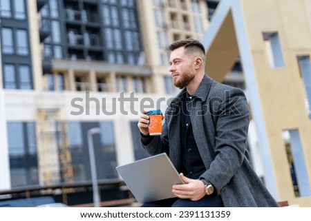 A man sitting on a bench with a laptop and a drink. The Contemplative Techie: A Man Engrossed in Work and Refreshment