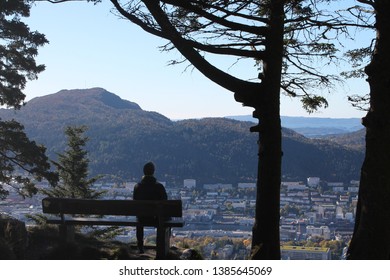 Man sitting on a bench over the city enjoying the view 