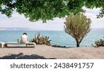 A man sitting on a bench overlooking the Sea of Galilee 