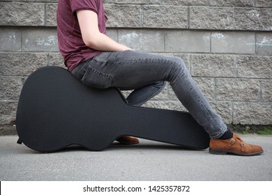 Man Sitting On A Black Guitar Case. Hard Case For Electric Guitar