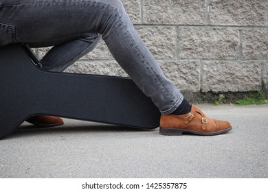 Man Sitting On A Black Guitar Case. Hard Case For Electric Guitar