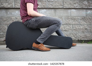 Man Sitting On A Black Guitar Case. Hard Case For Electric Guitar