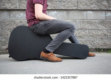 Man Sitting On A Black Guitar Case. Hard Case For Electric Guitar