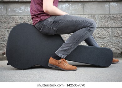 Man Sitting On A Black Guitar Case. Hard Case For Electric Guitar