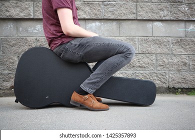 Man Sitting On A Black Guitar Case. Hard Case For Electric Guitar