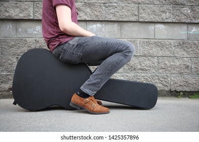 Man Sitting On A Black Guitar Case. Hard Case For Electric Guitar