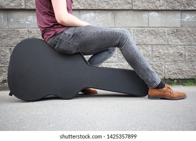 Man Sitting On A Black Guitar Case. Hard Case For Electric Guitar