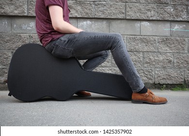 Man Sitting On A Black Guitar Case. Hard Case For Electric Guitar