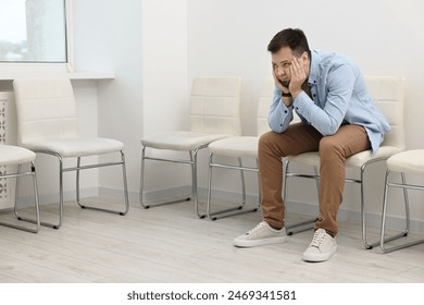 Man sitting on chair and waiting for appointment indoors