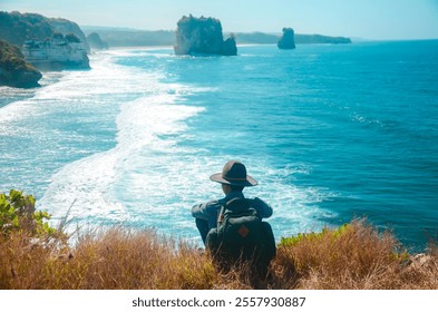 Man sitting on a cliff with beautiful landscape view on a rocky coast with wavy ocean - Powered by Shutterstock