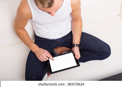 Man Sitting On Couch And Using Tablet